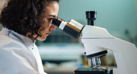 Laboratory technician peering through microscope