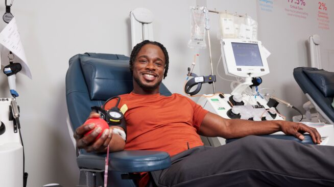 Smiling blood donor squeezing a red foam heart